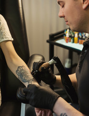 Professional tattoo artist making tattoo on hand