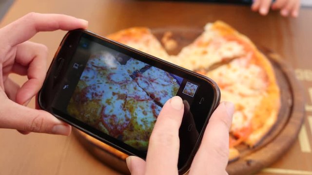Food photo taking picture of pizza via smartphone camera for social media