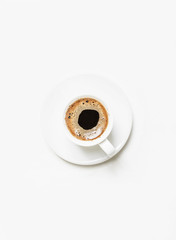 White cup of black coffee espresso with foam, white background, top view