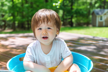 Happy toddler boy playing with water outside
