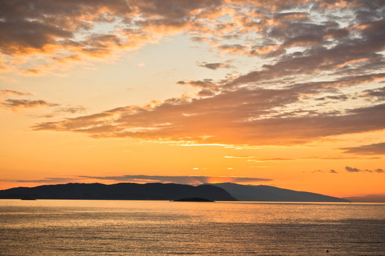 Sun is setting behind Skiathos island, view from Kastani Mamma Mia beach, island of Skopelos, Greece