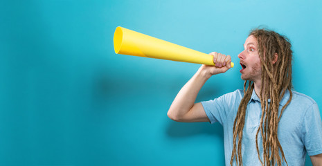 Young man holding a paper megaphone on a solid background