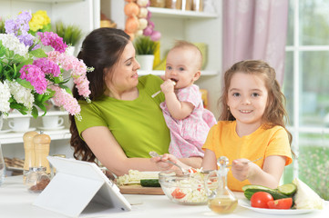 Obraz na płótnie Canvas Cute little girl eating fresh salad at kitchen table