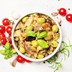 Stewed aubergines with vegetables and herbs in a bowl, light background, top view