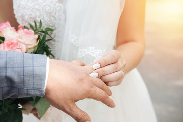 brideputs the ring on the groom's hand sunset