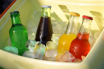 Colorful soda drinks and filled ice cubes in a cool box .