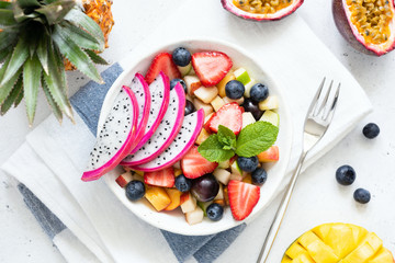 Tropical fruit salad with dragon fruit and mango in a bowl. Colorful exotic fruit salad on white...