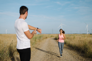 Young runners working out together in countryside. Athlete timing his trail running partner.