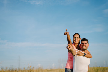 Couple of young man and woman embracing and pointing to the sky.