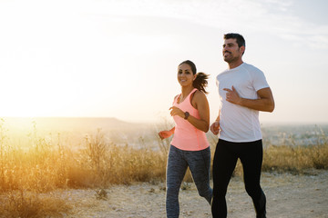 Two athletes running at sunset. Man and woman training together. - 207779833