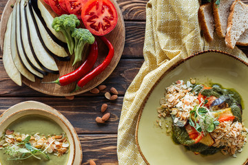 flat lay with vegetarian salad, cream soup and arranged fresh ingredients around on wooden tabletop