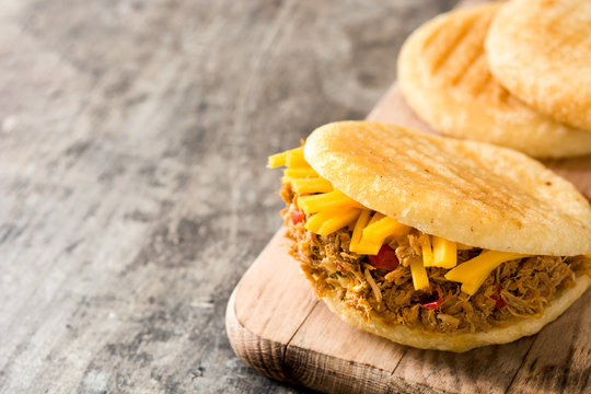Arepa with shredded beef and cheese on wooden background. Venezuelan typical food. Copyspace