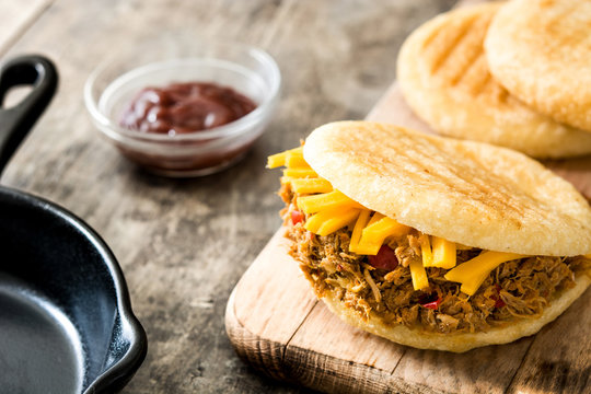 Arepa with shredded beef and cheese on wooden background. Venezuelan typical food