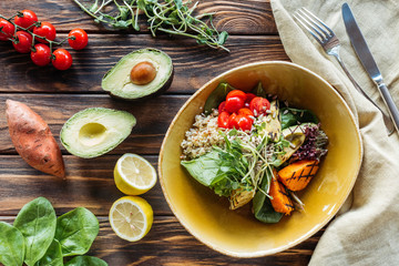 flat lay with vegetarian salad with grilled vegetables and sprouts, linen and cutlery on wooden surface