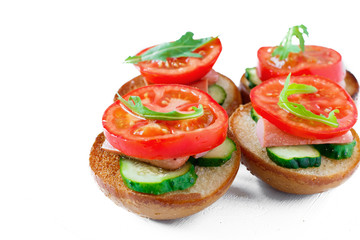 Sandwiches with sausages, cucumbers and tomatoes and arugula on a white background isolated