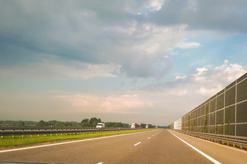 A view of the highway from the perspective of the driver and passenger. Dry asphalt, energy-intensive barriers and sky with clouds