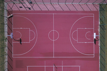 Modern basketball court under the open sky with artificial red coating. Location of team sports events. Physical education of citizens. Healthy lifestyle. View of bird`s fly: drone, aircraft.