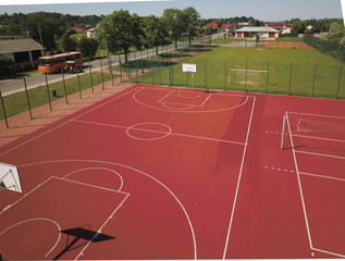 Modern basketball court in the courtyard of primary school. Multifunctional children's playground with artificial surfaced fenced with mesh fence.Place of physical education of children and young.
