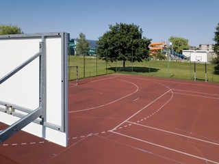 Modern basketball court under the open sky with artificial red coating. Location of team sports...