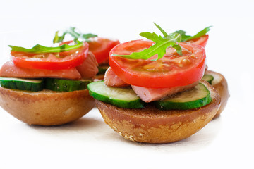 Sandwiches with sausages, cucumbers and tomatoes and arugula on a white background isolated
