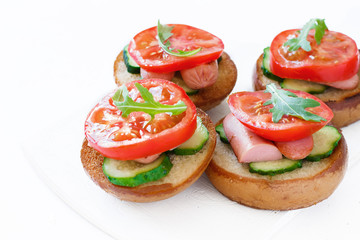 Sandwiches with sausages, cucumbers and tomatoes and arugula on a white background isolated