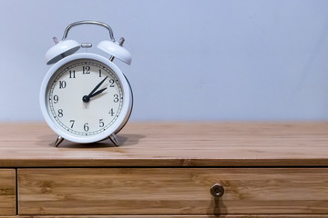 White alarm clock on wooden desk