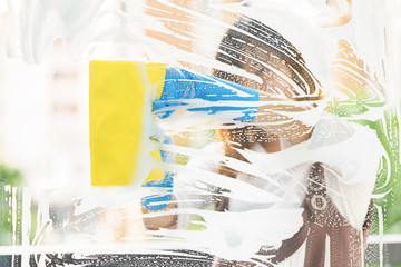 Woman housekeeper cleaning the mirror with yellow sponge