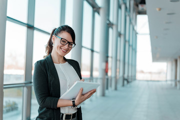 Successful and satisfied businesswoman, holding a notebook,looking at camera.