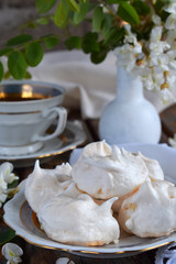 Meringues cookies and cup of coffee. Homemade Meringue kisses drops with acacia flowers. Vintage photo. Copy space