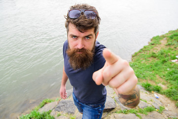 Man with beard and mustache with sunglasses, riverside on background. Pointing and direction...