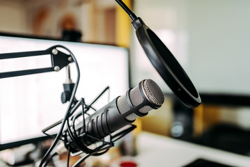 Close-up image of microphone and white computer screen in the background.