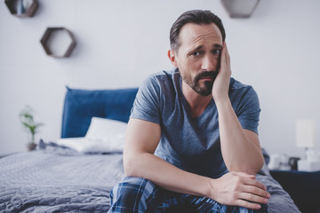 man with toothache sitting on bed