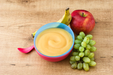 Baby food: colorful bowl of fruit puree on wooden table. 