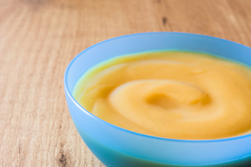 Baby food: colorful bowl of fruit puree on wooden table. Copyspace