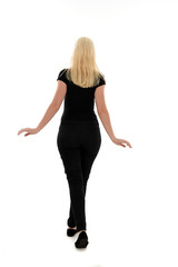 full length portrait of blonde girl wearing black clothing, isolated on white background.