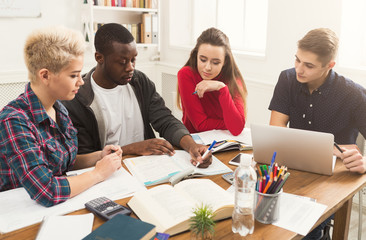 Group of diverse students studying at wooden table