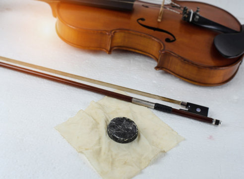 In selective focus of used rosin for violin,put beside bow,blurry light design background.