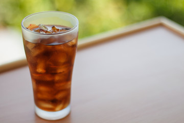 Cola in glass with ice cubes and blur background. Sparkling water soft drinks.