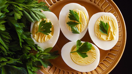 Delicious boiled eggs and parsley on black background.