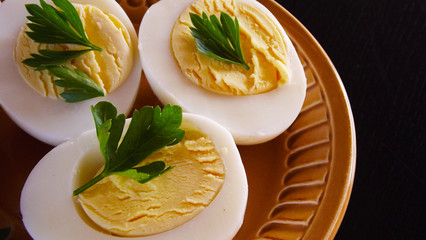 Delicious boiled eggs and parsley on black background.