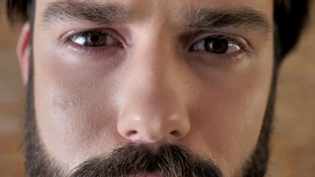 Eyes of young serious man with mustache, sadness, watching at camera