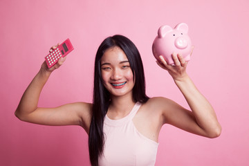 Asian woman with calculator and piggy bank.