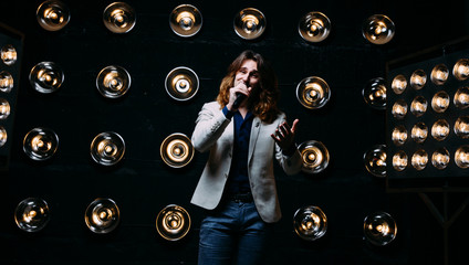 men singer with long hair, with microphone on the stage