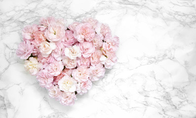 Heart made of pink carnations on marble background. Flat lay, top view