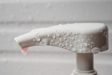 Water drop on liquid soap dispenser pump during bath time