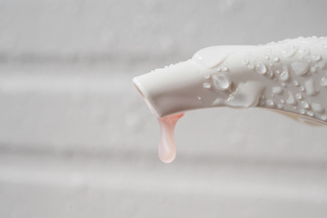Water drop on liquid soap dispenser pump during bath time