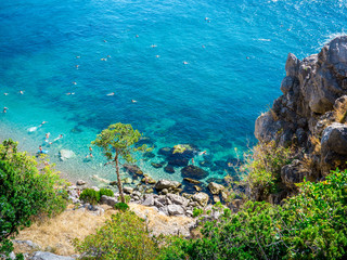 The top view and the beach. View from the high rocky shore. Azure-blue clear water. People swim in the beach. Black sea, Crimea