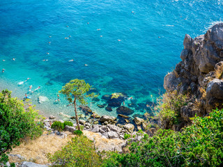 The top view and the beach. View from the high rocky shore. Azure-blue clear water. People swim in the beach. Black sea, Crimea