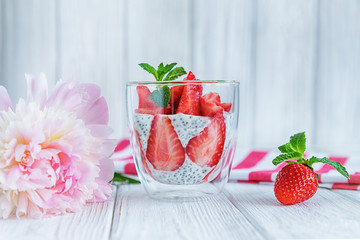 Chia pudding with fresh strawberries and mint in glass on white background. Summertime. Concept of healthy eating