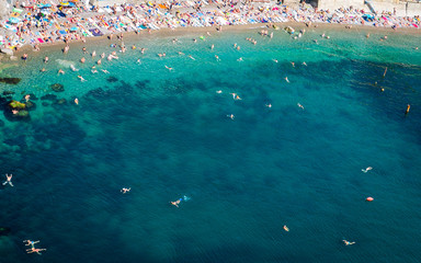 Fototapeta na wymiar The top view and the beach. View from the high rocky shore. Azure-blue clear water. People swim in the beach. Black sea, Crimea